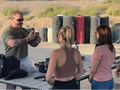 Group of people at a shooting range with instructor taking photos.
